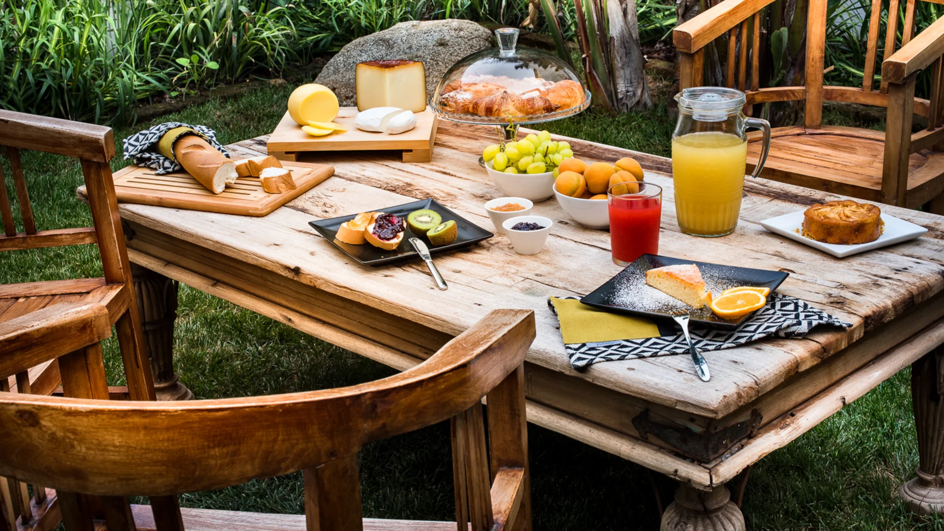Colazione all’aperto su un tavolo di legno con formaggi, frutta, pane e succhi