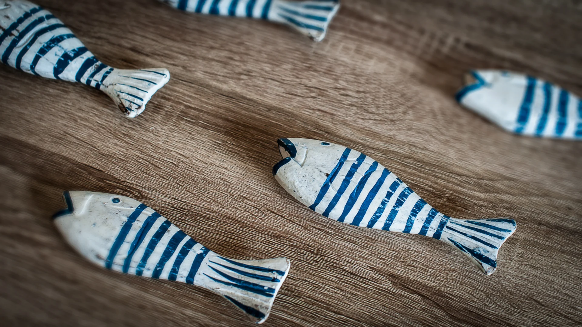 Decorazioni a forma di pesce bianche e blu su una superficie di legno