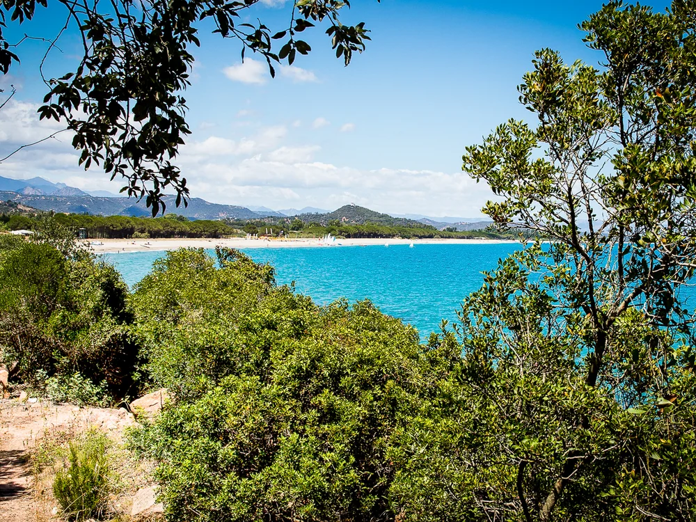 Teku Boutique Hotel a Bari Sardo – l’Ogliastra più autentica Vista su una baia turchese e una spiaggia sabbiosa tra alberi e montagne