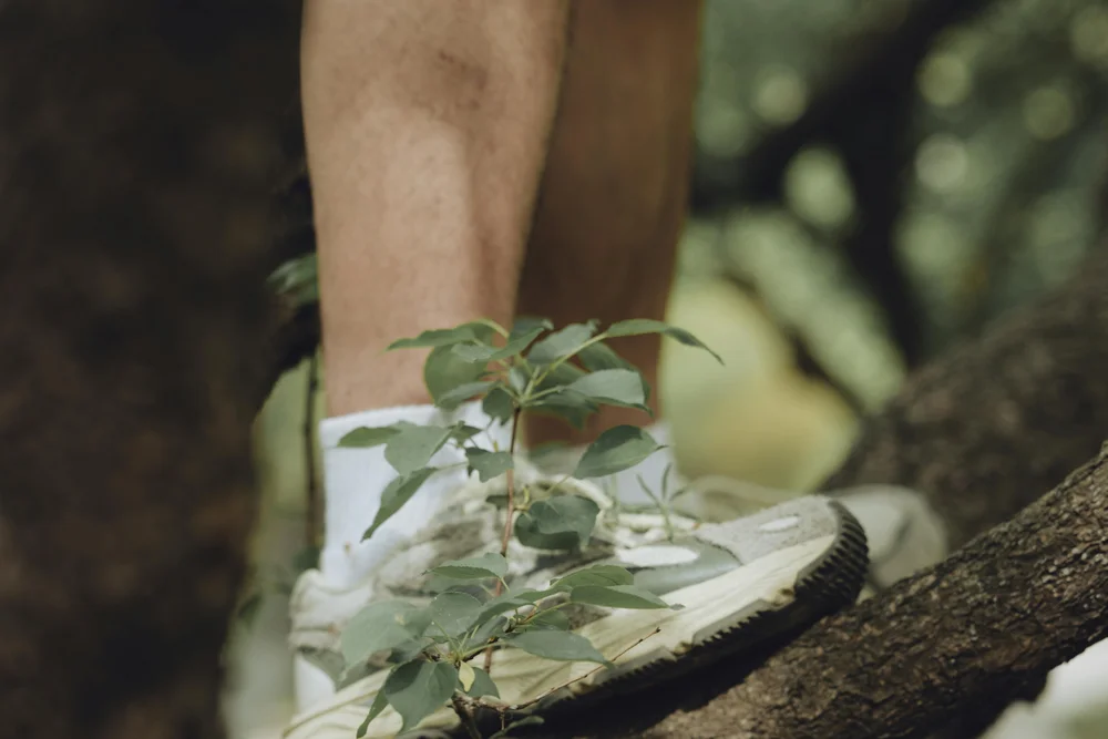 Persona con scarpe da ginnastica bianche in equilibrio su un ramo nel bosco