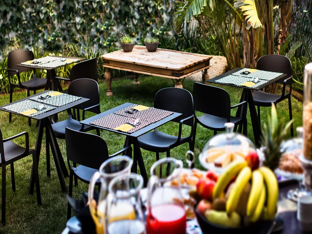 Teku Boutique Hotel a Bari Sardo – l’Ogliastra più autentica Tavoli e sedie in un giardino, con frutta e bevande in primo piano