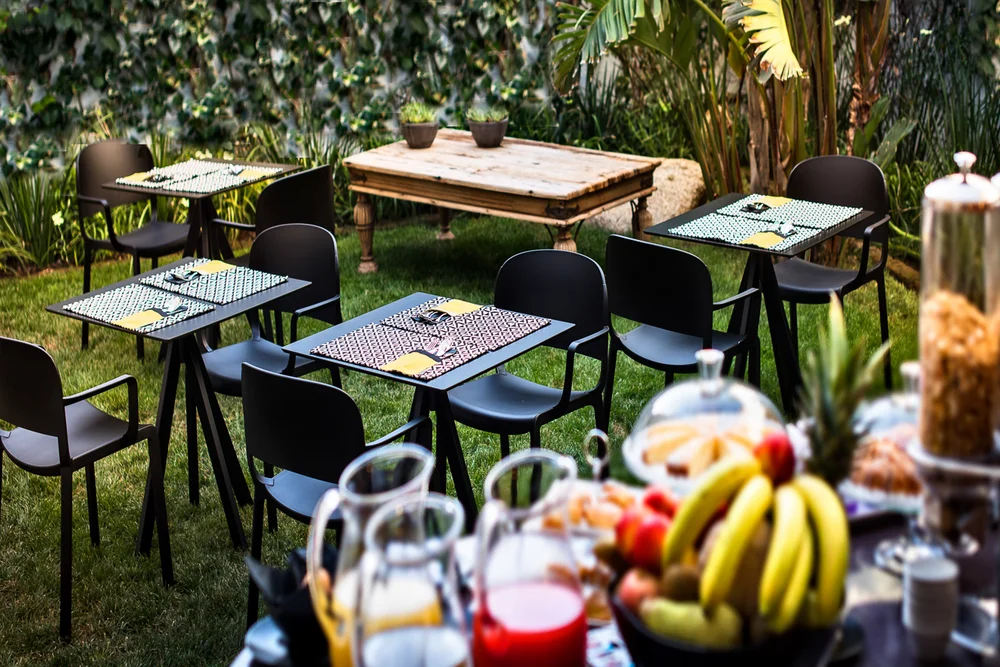Tavoli e sedie in un giardino, con frutta e bevande in primo piano