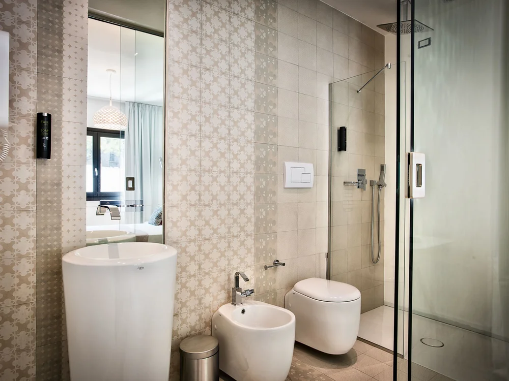 Teku Boutique Hotel a Bari Sardo – l’Ogliastra più autentica Bagno moderno con lavabo freestanding, bidet, WC e doccia in vetro