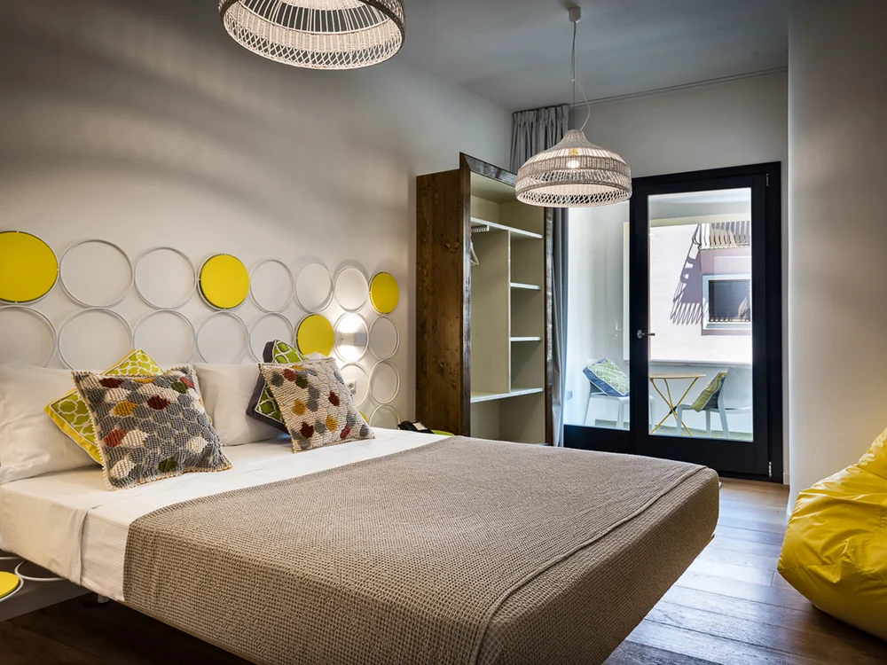 Teku Boutique Hotel a Bari Sardo – l’Ogliastra più autentica Camera da letto moderna con letto matrimoniale, parete decorata a cerchi e porta finestra
