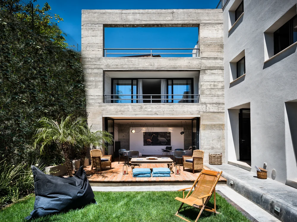 Teku Boutique Hotel a Bari Sardo – l’Ogliastra più autentica Cortile moderno con prato, terrazza arredata e facciata in cemento a vista